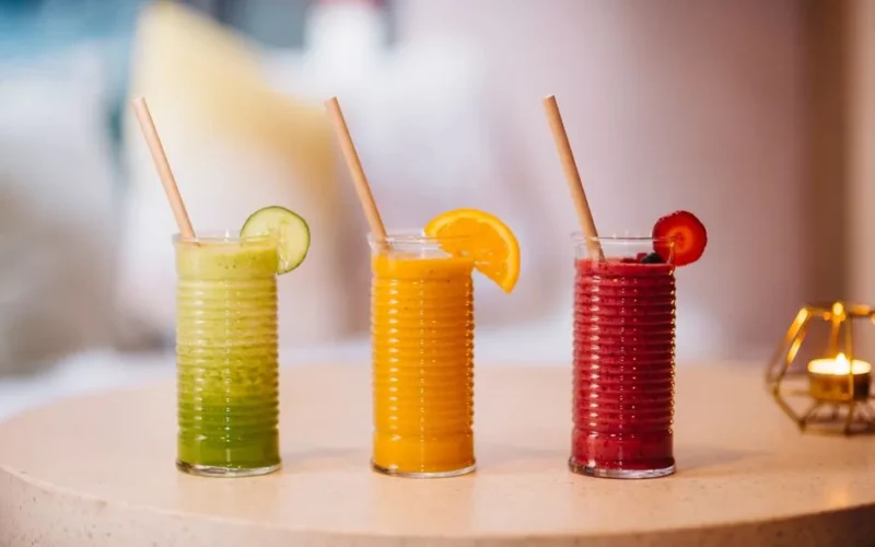 Three vibrant fruit smoothies with bamboo straws, perfect for a refreshing summer drink.
