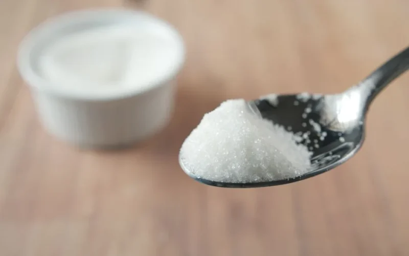 A close-up shot of granulated sugar on a spoon, highlighting texture and shine.