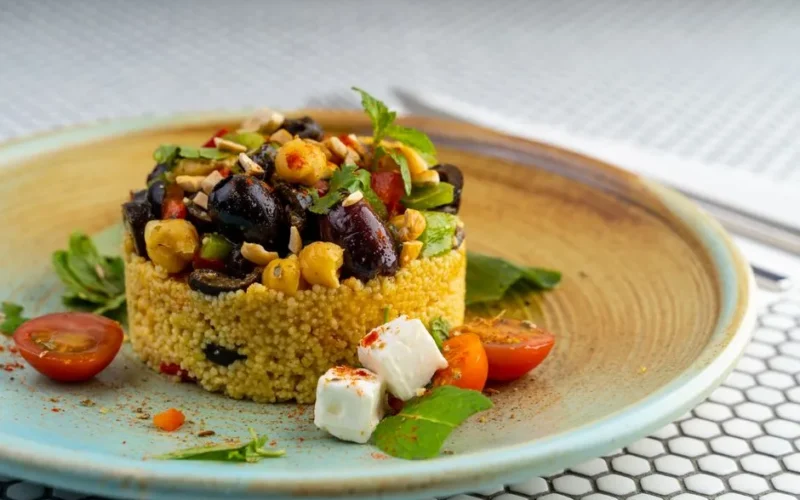 Delicious couscous salad with olives, chickpeas, and cherry tomatoes on a modern plate.