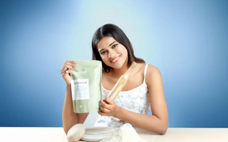 Smiling woman holding Goya flour with rolling pin, ready for baking indoors.
