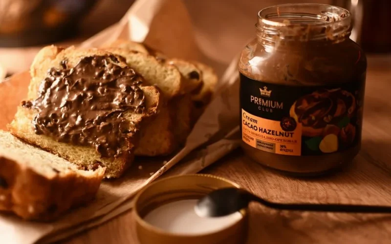 Appetizing image of cacao hazelnut spread on fresh sliced bread, perfect for a hearty breakfast.