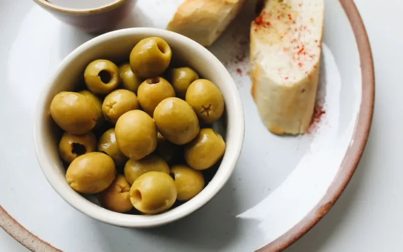 A delicious serving of green olives and sliced bread, perfect for a light snack.