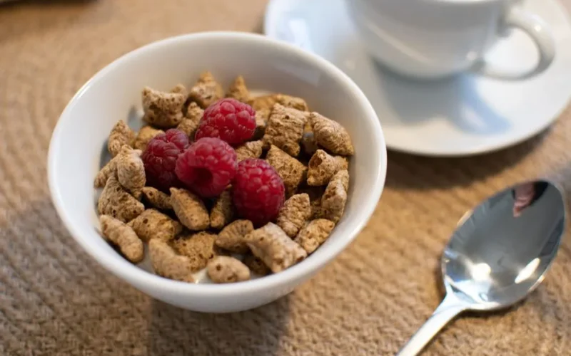 Enjoy a nutritious breakfast with whole grain cereal and fresh raspberries, perfect for a healthy start to your day.