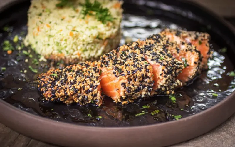 Close-up of sesame-crusted salmon with a side of couscous, perfect for gourmet food lovers.