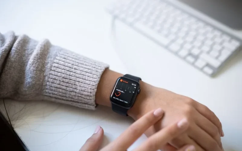 Close-up of a person checking health stats on a smartwatch in an office environment.