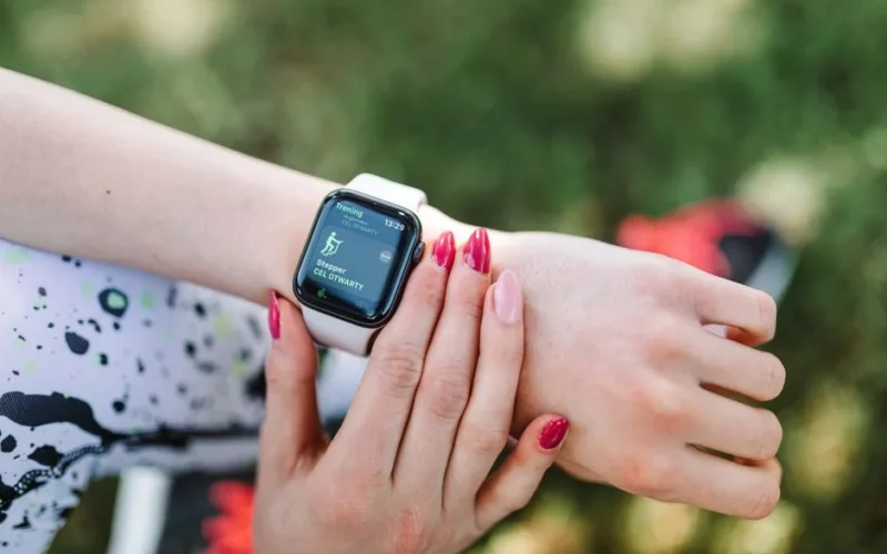 Close-up of a woman using a fitness tracking smartwatch during exercise outdoors.