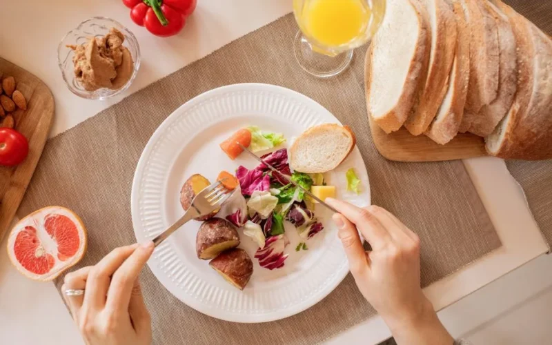 Top view of a nutritious breakfast setup with salad, bread, and fresh juice, perfect for a healthy start.