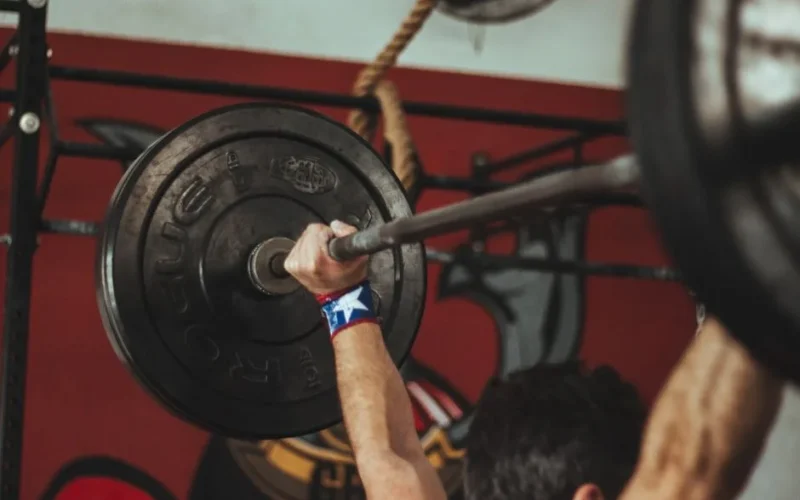 Athlete lifting heavy barbell during strength training session in gym.
