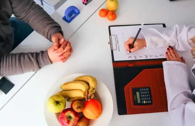 Top view of a dietitian planning a healthy diet with fresh fruits on the table, focusing on health and nutrition.