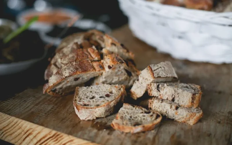 Close-up of freshly sliced artisan bread on a rustic wooden board, perfect for breakfast or snacks.