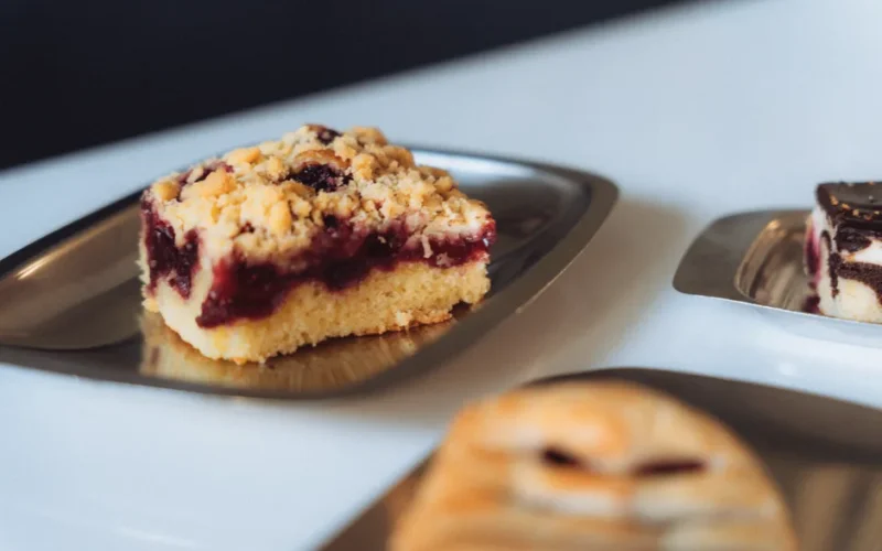 Close-up of a piece of streuselkuchen with berry filling on metal plate.