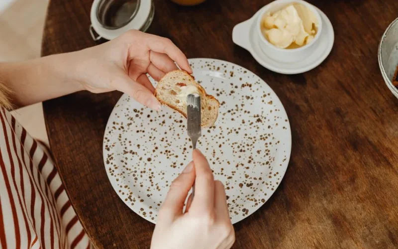 Close-up of a person spreading butter on bread for a delicious breakfast.