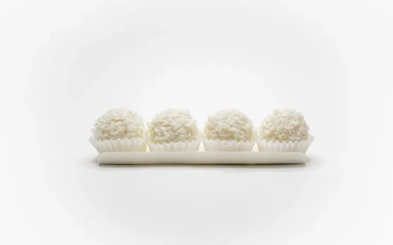 Set of four white coconut pralines, elegantly arranged in a minimalist style on a white background.