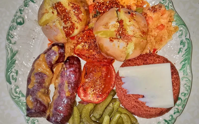 Salchichón sausage, roasted Roma tomato, boiled yellow potatoes, sauerkraut with mixed vegetables, Boston brown bread with cheddar cheese, and cornichons, with salt, pepper, two mustards, and chili powder - Massachusetts, USA.