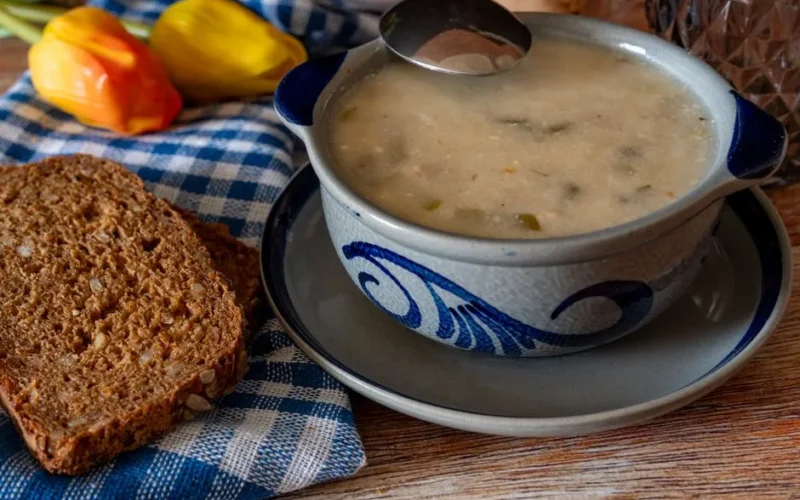 Delicious homemade vegetable soup served with wholegrain bread on a rustic table setting.