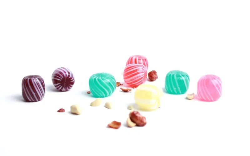 A vibrant assortment of striped candies scattered on a white backdrop, exuding sweetness and playfulness.