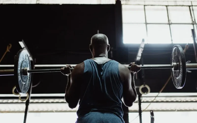 A muscular man lifting a barbell indoors, showcasing strength and fitness.