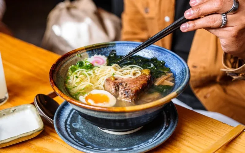 A vibrant bowl of ramen with chopsticks, showcasing a perfect mix of ingredients.