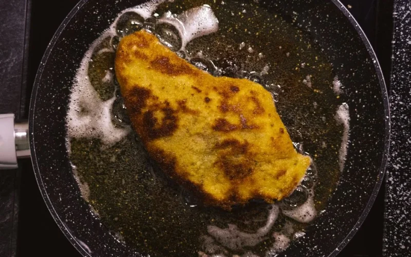 Golden schnitzel frying in a pan, capturing the essence of home-cooked comfort food.