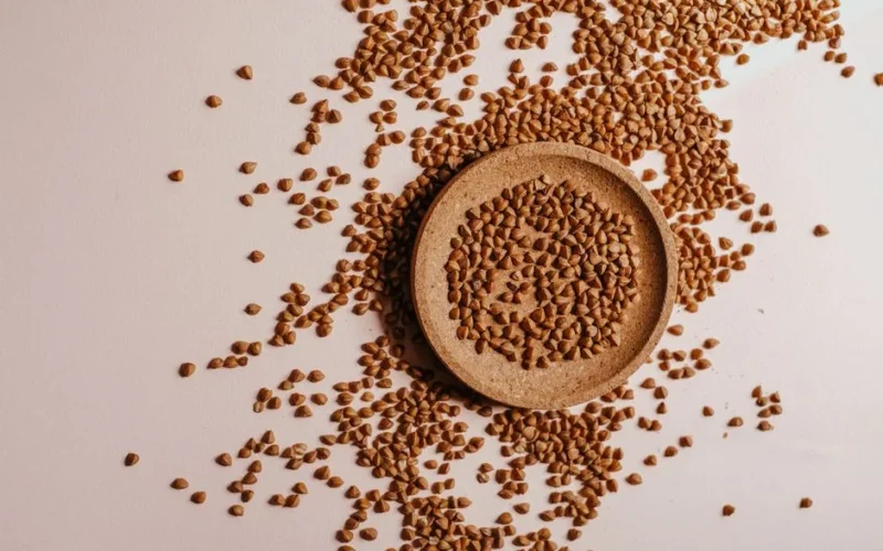 Flat lay of organic buckwheat groats on a wooden plate, perfect for healthy food photography projects.
