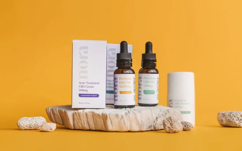 Close-up of CBD oil bottles and cream on a yellow background with natural textures.