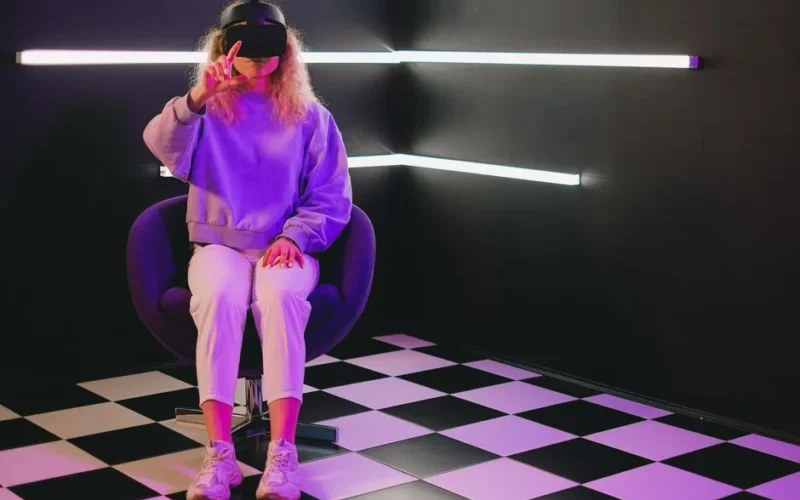 Woman in VR headset experiencing virtual reality in a futuristic indoor setting.