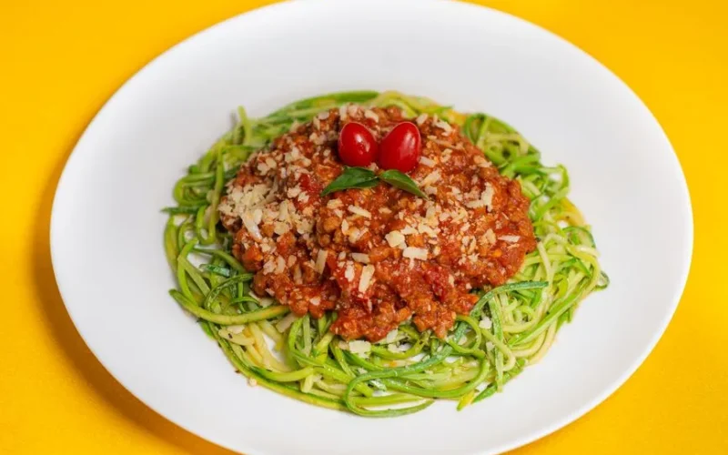 A vibrant dish featuring zucchini noodles topped with savory Bolognese and cherry tomatoes.