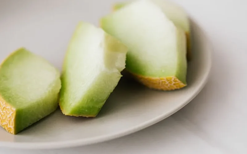 Closeup of small plate of slices of ripe melon placed on white table