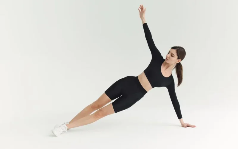 Woman performing a side plank exercise indoors, showcasing strength and balance.