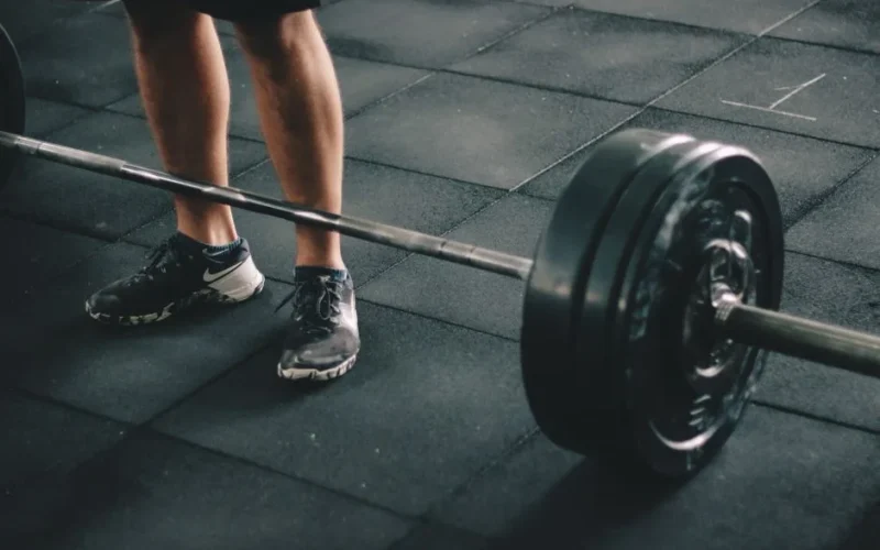 Close-up of a man deadlifting a heavy barbell in an indoor gym setting.