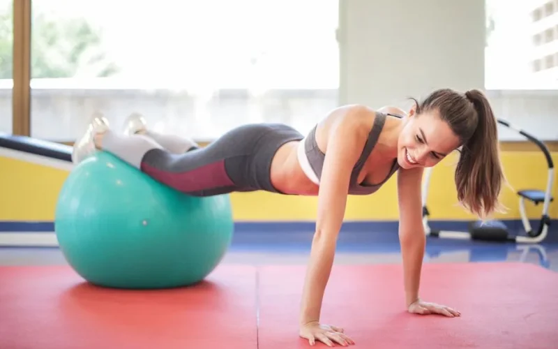 Active woman performing a workout with a stability ball indoors, showcasing fitness and strength.