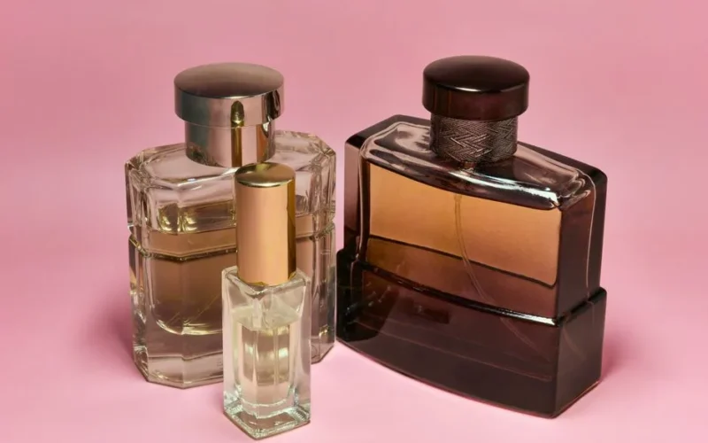 Three stylish perfume bottles with elegant caps on a pink backdrop, capturing a sense of luxury and sophistication.