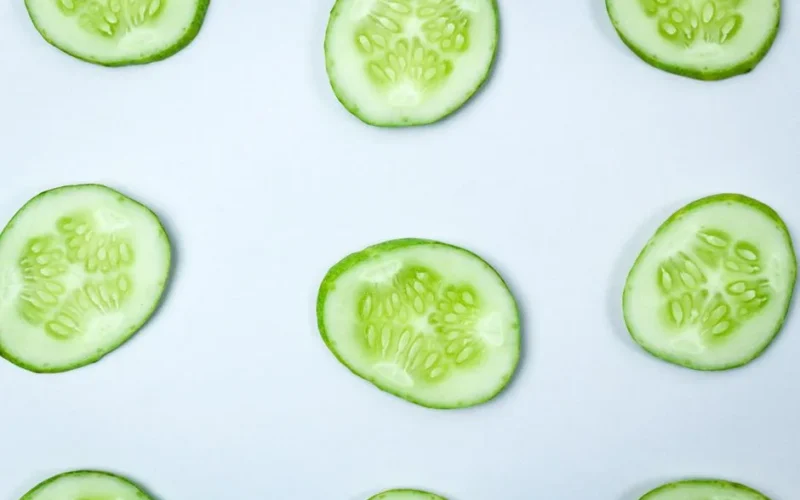 Close-up of fresh cucumber slices in a flatlay pattern on a white background.