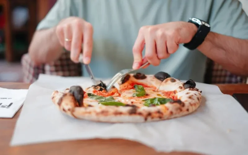 Close-up shot of a man eating pizza in an Italian restaurant, showcasing vibrant toppings.
