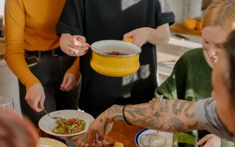 A group of friends enjoying a veggie meal together in a bright kitchen setting.