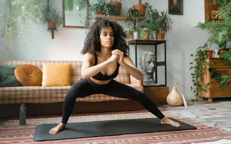 A woman exercises on a yoga mat surrounded by indoor plants, capturing a healthy lifestyle.