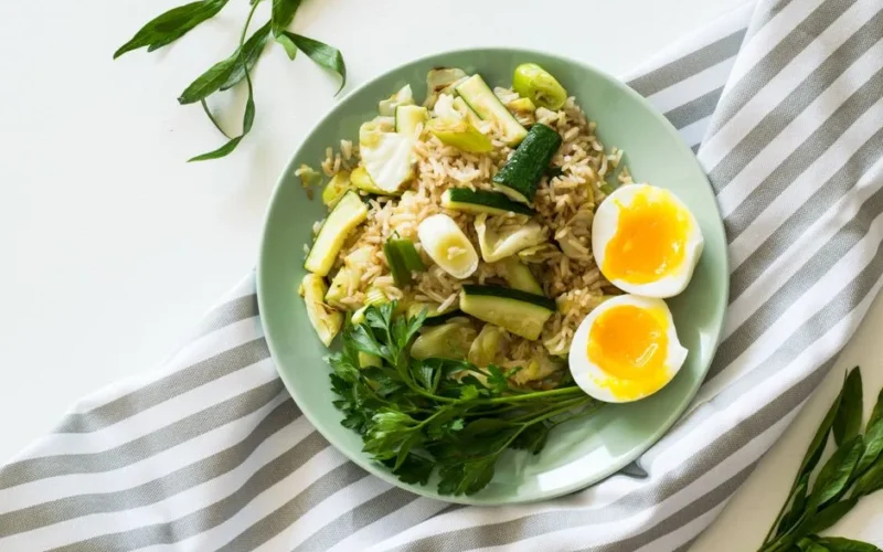 Delicious rice meal with zucchini, greens, and soft-boiled egg, perfect for a healthy diet.