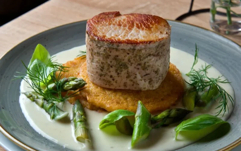Delicious pork dish with asparagus, fresh greens, and creamy herb sauce.