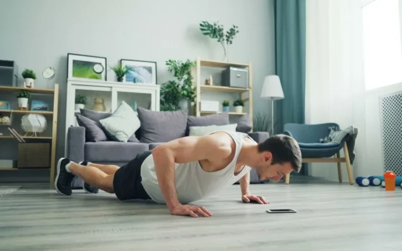 A muscular man performing push-ups in a modern living room, showcasing home fitness.