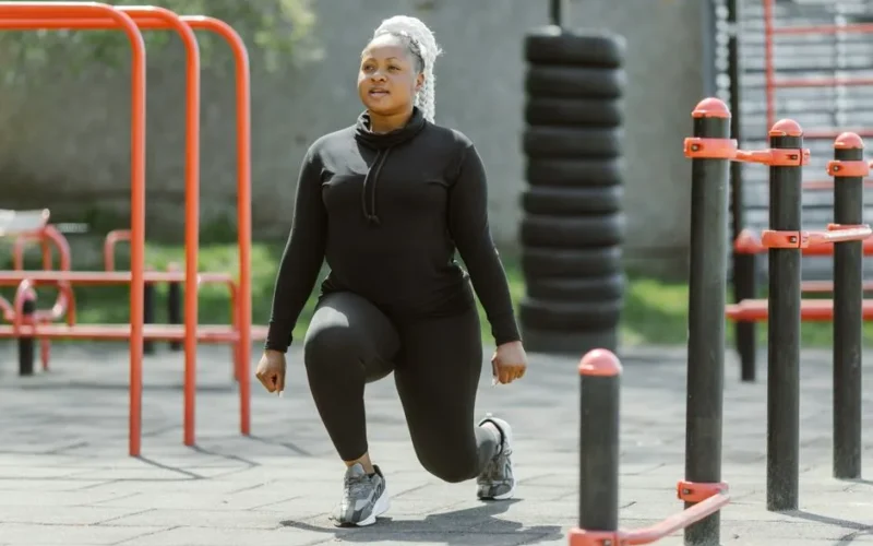 Fit woman performing lunges at an outdoor gym, embracing a healthy lifestyle.