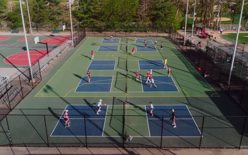 A lively pickleball game at outdoor courts in Philadelphia, captured from above on a sunny day.