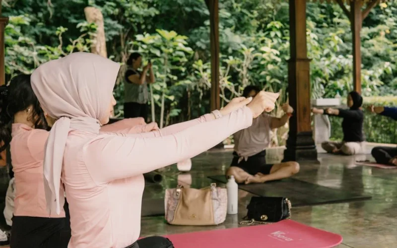 Women practicing yoga outdoors in a serene pavilion setting in Indonesia.