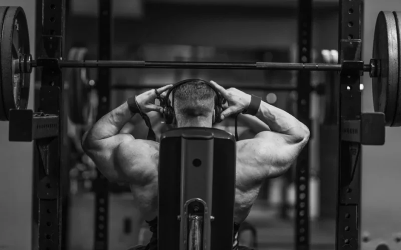 Muscular man lifting weights in a gym setting, showcasing strength and fitness.