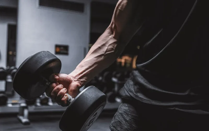 Close-up of a muscular arm holding a dumbbell, emphasizing strength and fitness.
