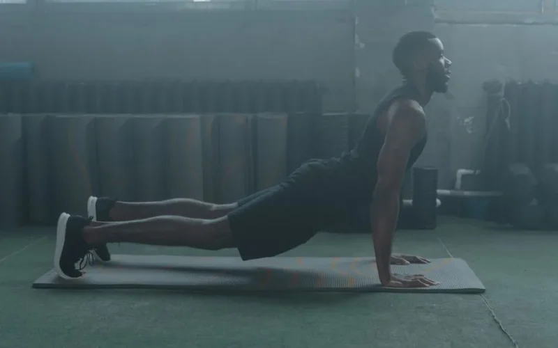 A man performing a yoga pose on a mat in a gym setting, embracing healthy living.
