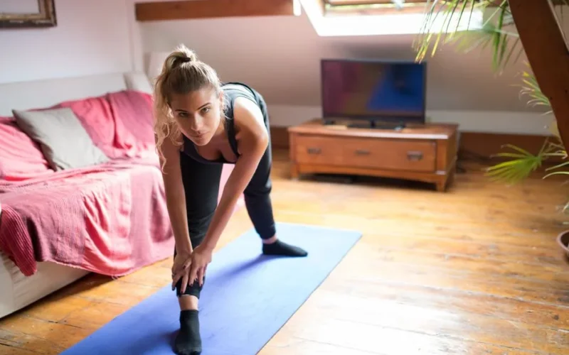 Woman exercising indoors on a yoga mat, stretching and staying fit at home.