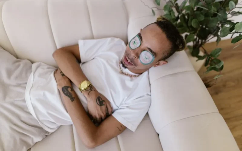 Man lying on a sofa with eye patches enjoying a calming home spa experience.