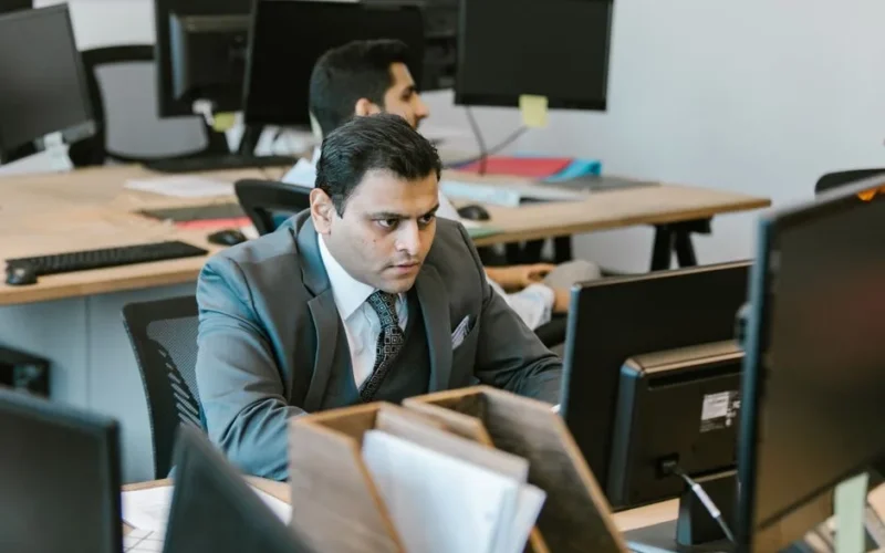 A dedicated businessman in a suit concentrating on work at a modern office desk.