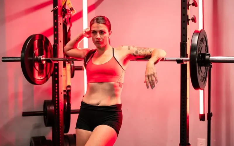 A determined woman in a gym setting, showcasing strength and athleticism with a barbell.