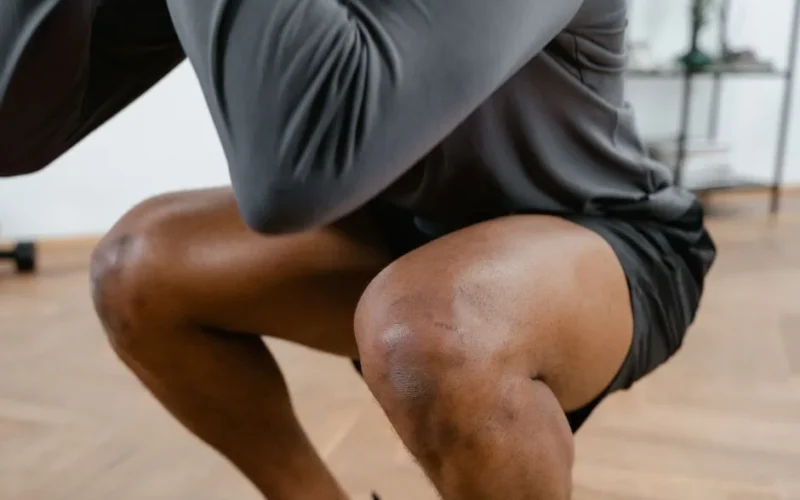 A focused view of a male athlete performing squats in a gym setting, emphasizing fitness and strength.